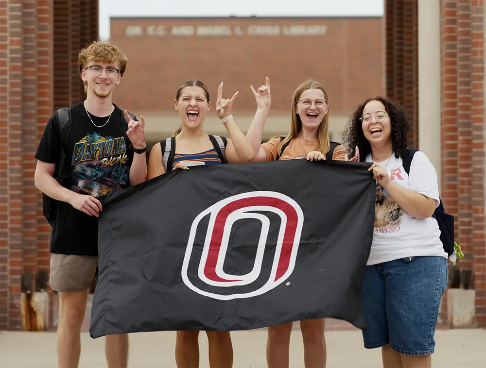 four students holding a UNO flag
