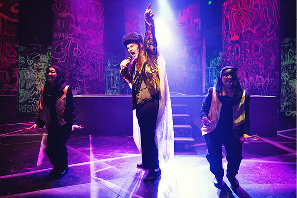 Performers dance on stage in colorful lighting at a local venue.