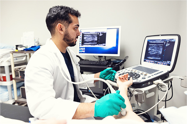 Student uses medical imaging equipment in a clinical lab setting.