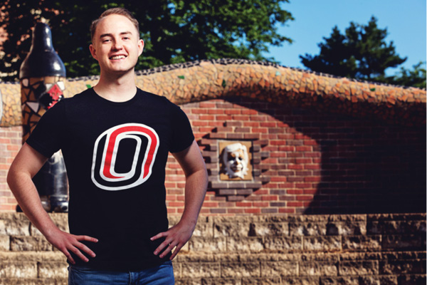 A student stands in front of a brick arch on campus.