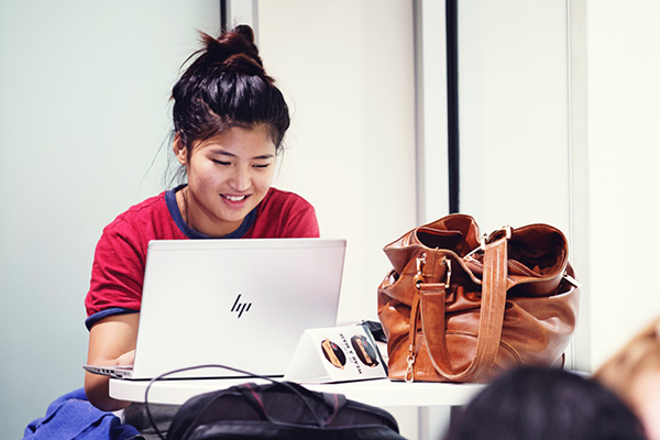A student works on a laptop in a study lounge.