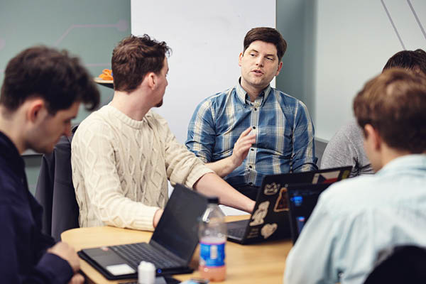 A group of graduate students at a table discussing a project.