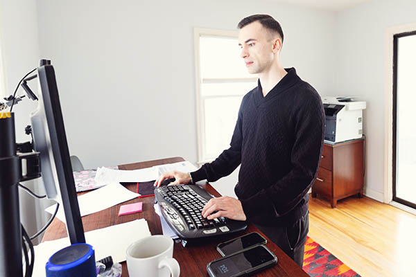 A student works at a standing desk in a home office.