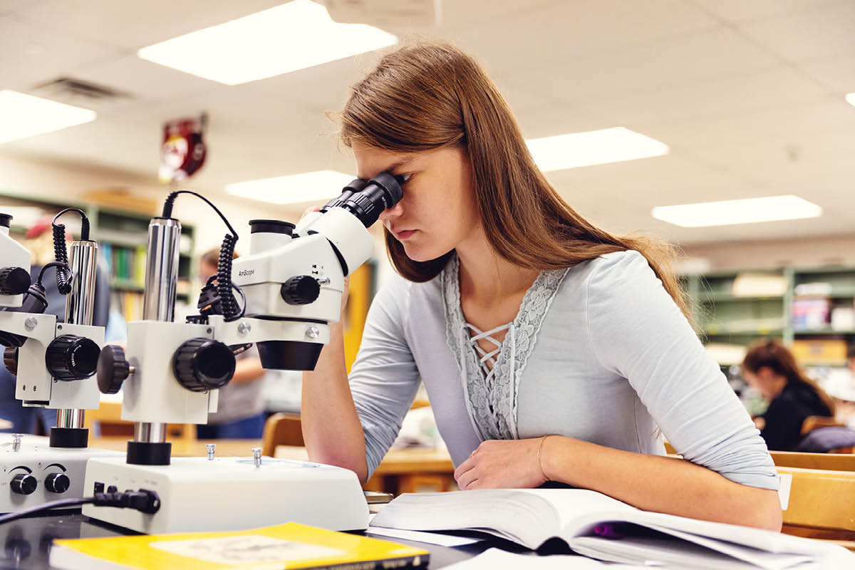 A student studies through a microscope in a campus science lab.