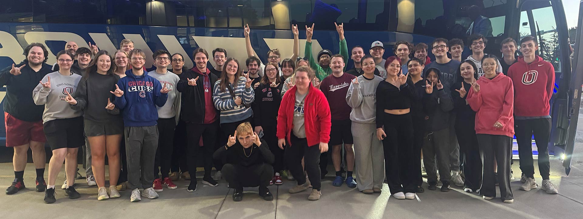 UNO students standing in front of a charter bus