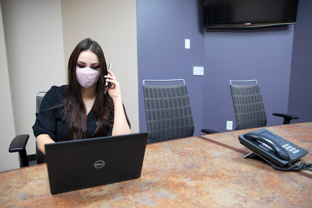 a young woman wearing a mask sits at a table.