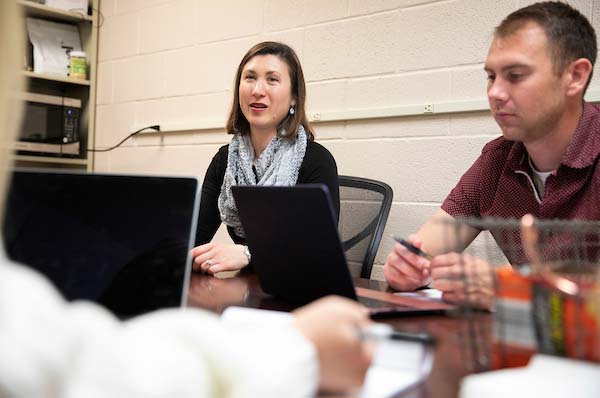 Christine Cutucache, Ph.D. speaking at a table of people.