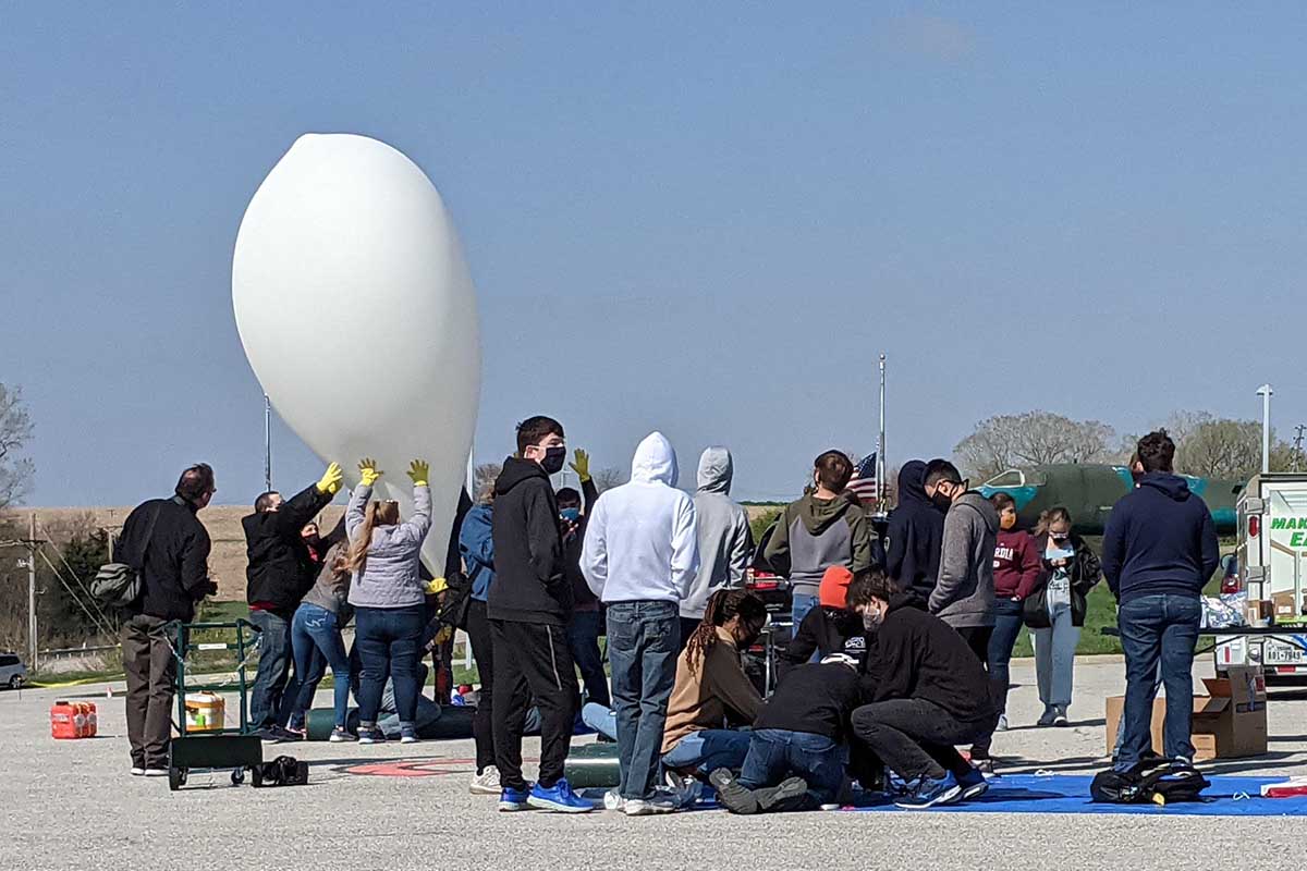 Students steady a high altitude balloon against harsh winds as it inflates at a special launch from the Strategic Air and Space Museum near Ashland, NE on April 24, 2021.