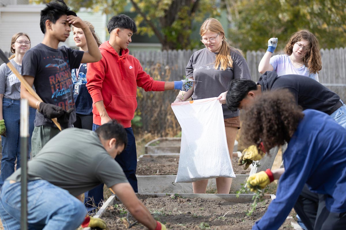 UNO students volunteering at Together Inc, participating in a service-learning course, by working together in a community garden.