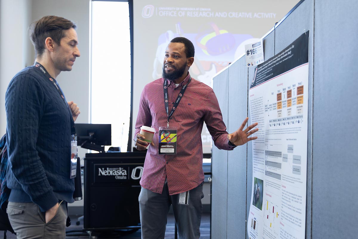 A student shares their poster presentation at the Research and Creative Activity Fair (RCAF) inside of UNO's Barbara Weitz Community Engagement Center.