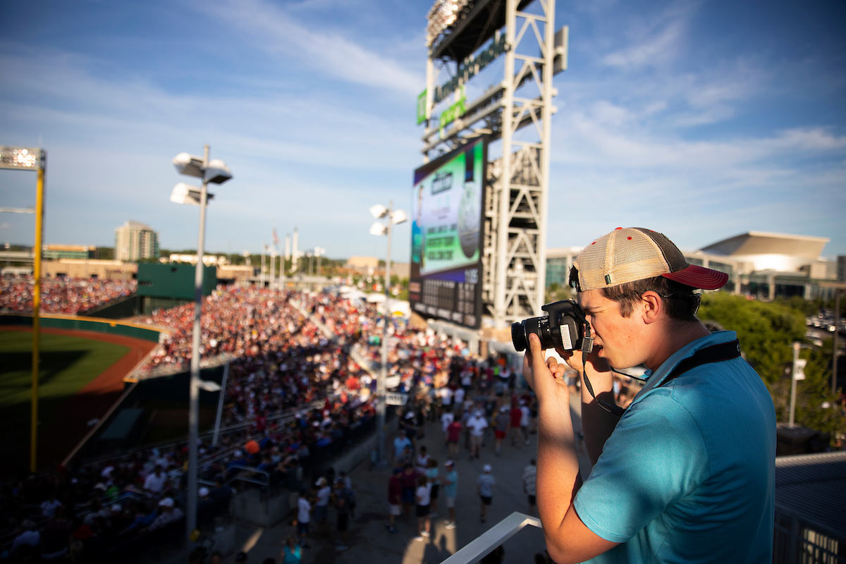 Mav Radio's Benjamin Helwig takes photos from the upper deck in right field as he captures the scene of the College World Series at TD Ameritrade Park
