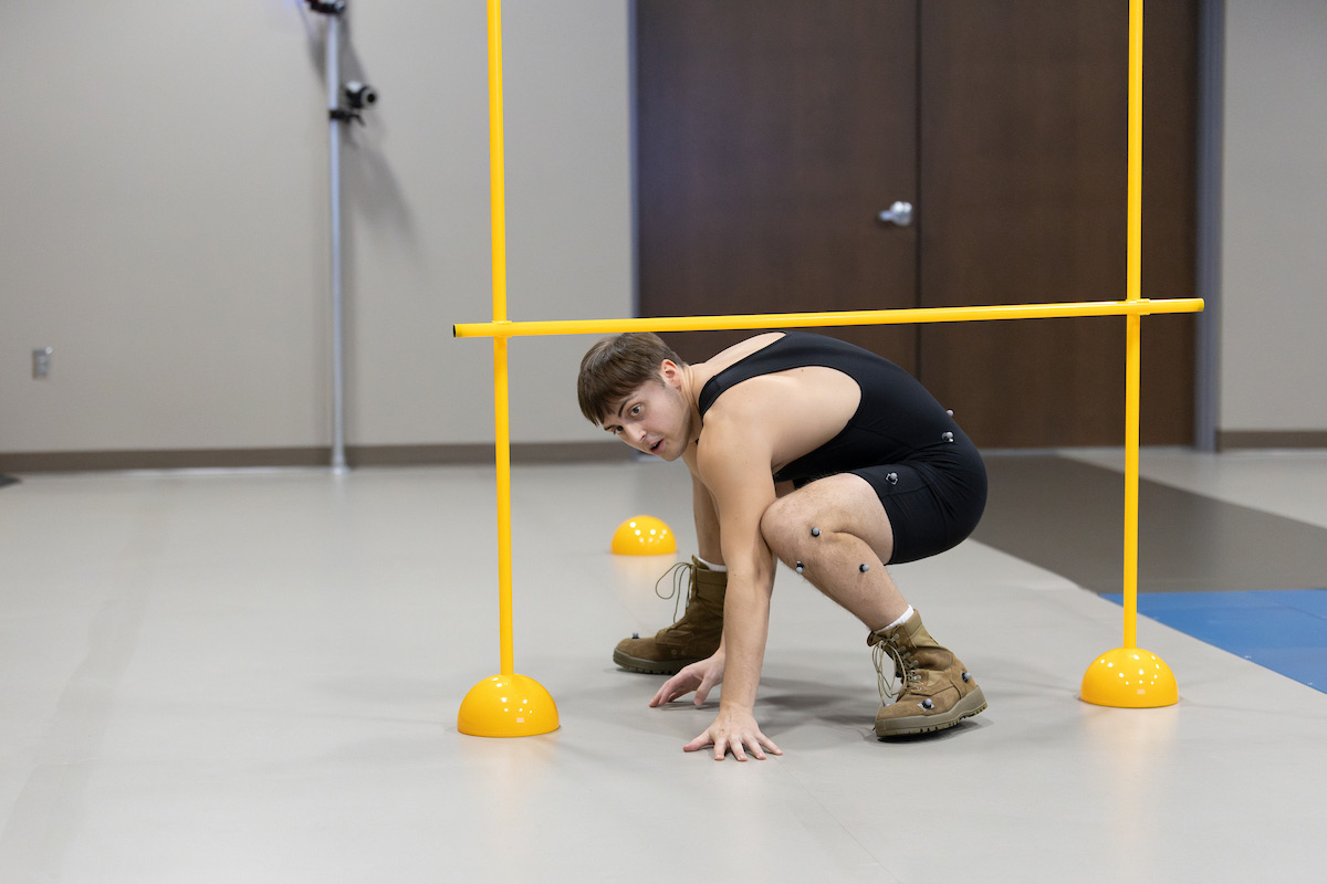 A subject tests a FlyBand® ExoBoot prototype at the University of Nebraska at Omaha Biomechanics Research Building by ducking under a crossbar.