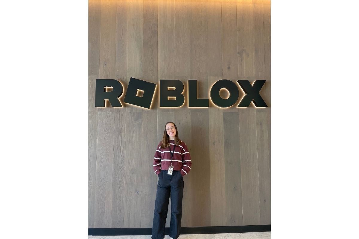 Averie Linnell poses in front of the glowing Roblox sign.