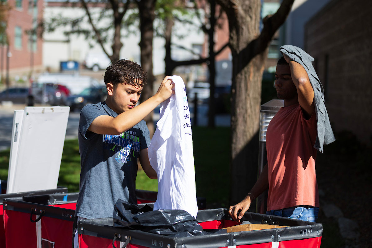 Two students sort through donated clothing from large bins during the Durango’s Outfitters event.