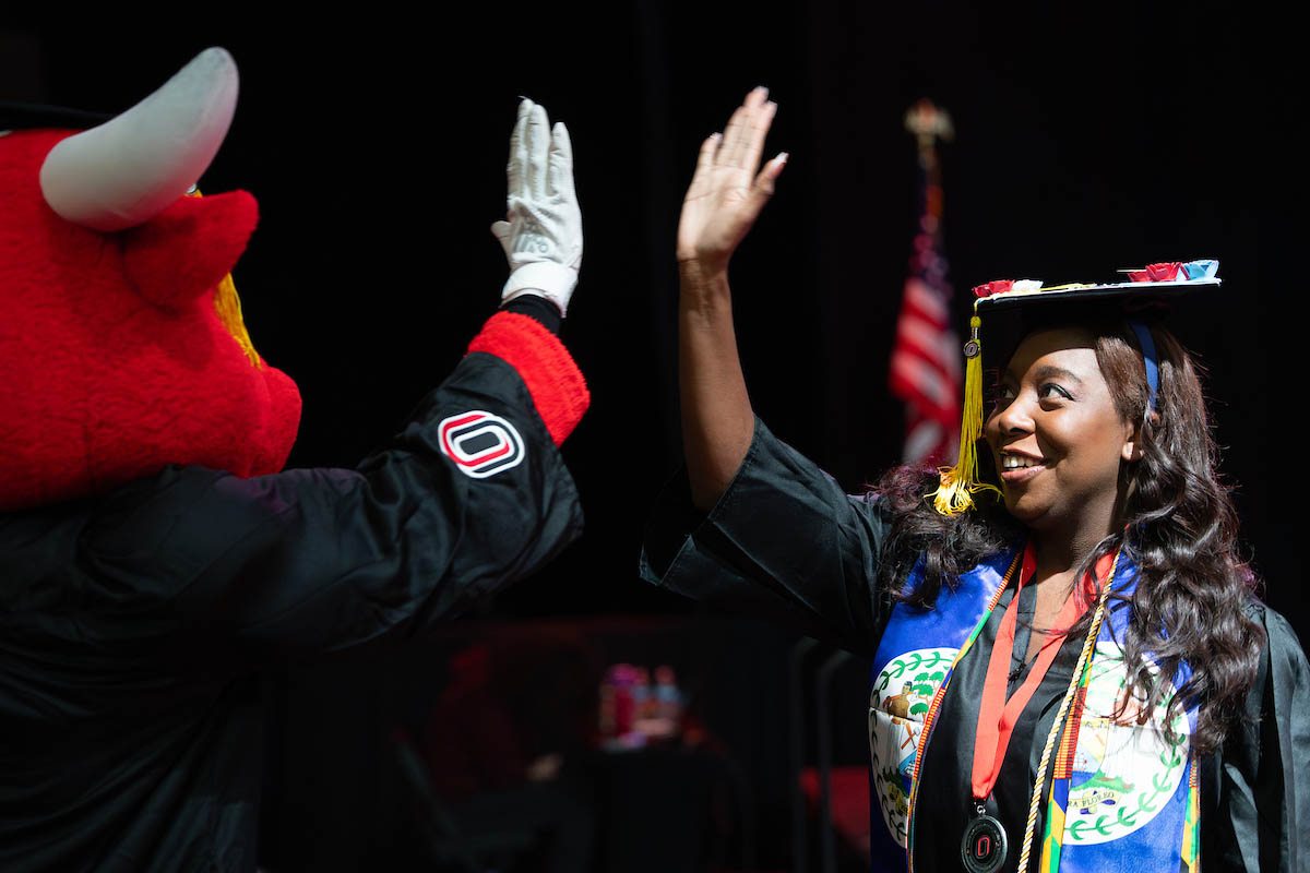 Durango and a graduate exchange a high five on stage during the commencement ceremony