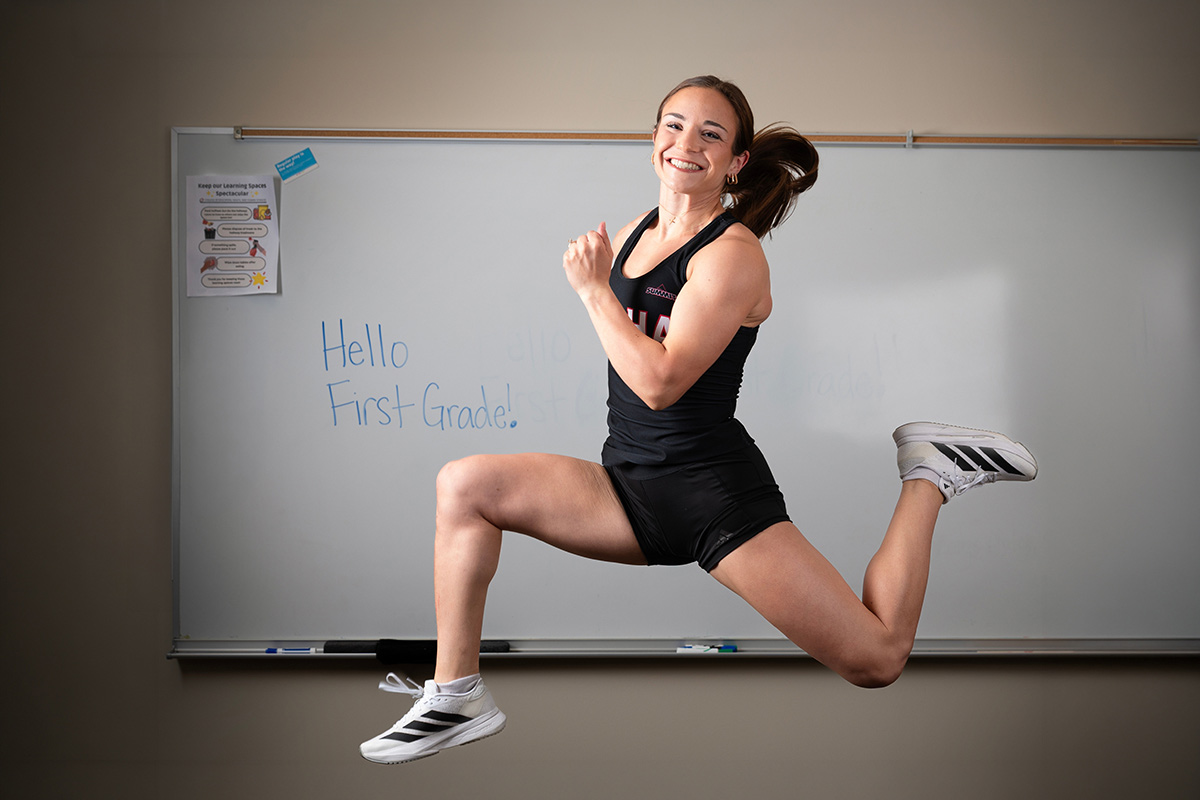 Emma Klein jumps in front of a white board with “Hello First Grade!” written on it. 
