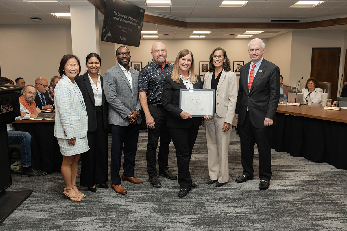 Denise Kjeldgaard poses with her certificate along with her husband, colleagues, and administration officials.
