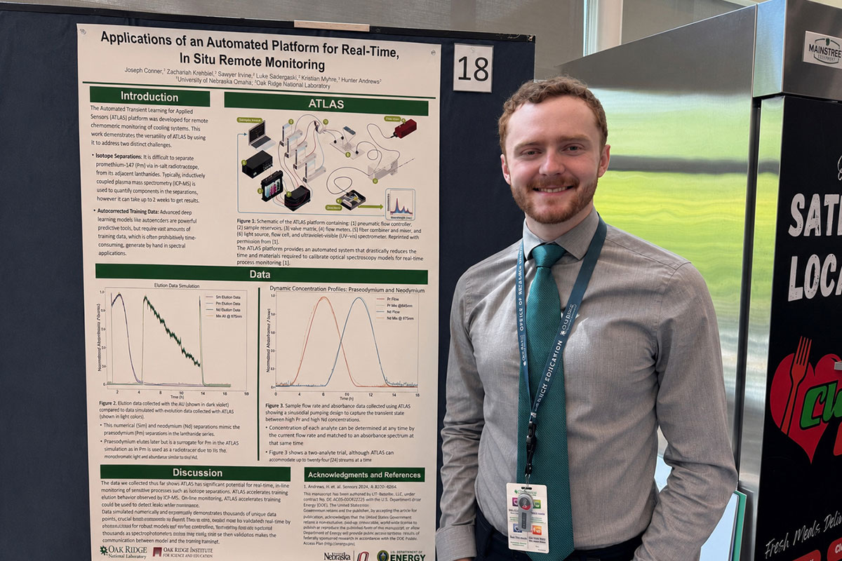 A man stands next to a poster detailing research 