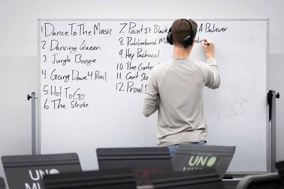 Spirit band member draws song names on a whiteboard.