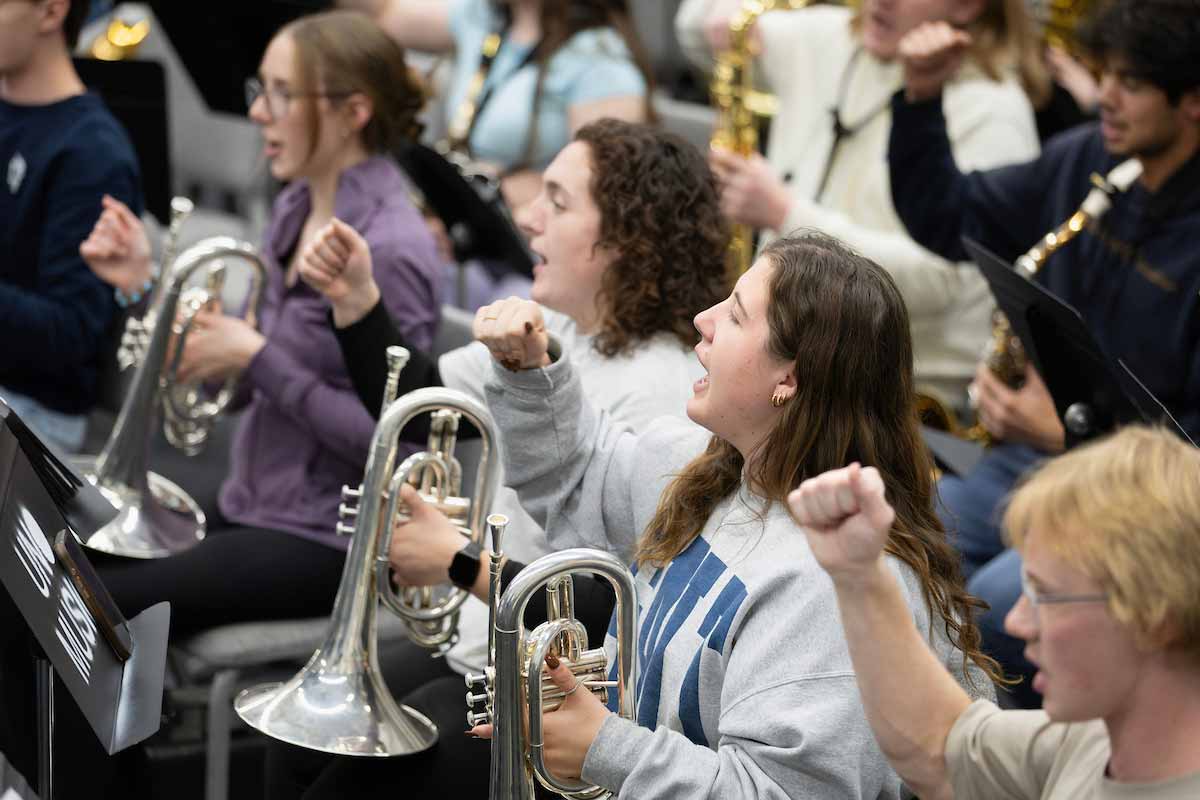 Spriit band members pump their fists and sing along to a song.  