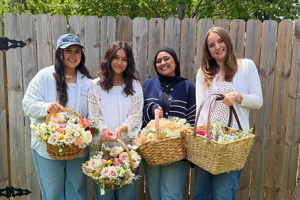 Four individuals stand with baskets full of flowers 