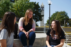 student sitting in front of student center