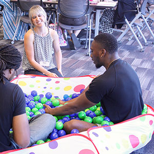 students sit in a blow up pool full of plastic balls.