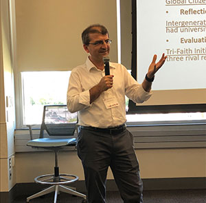 a professor holds a microphone in front of a class.