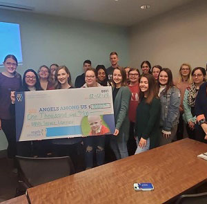 a group of people stand together holding a large donation check.