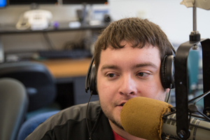 a male student wearing headphones speaks into a microphone.
