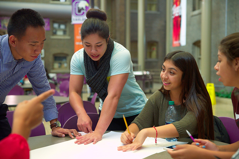 a group of students sit at a table work together on a project
