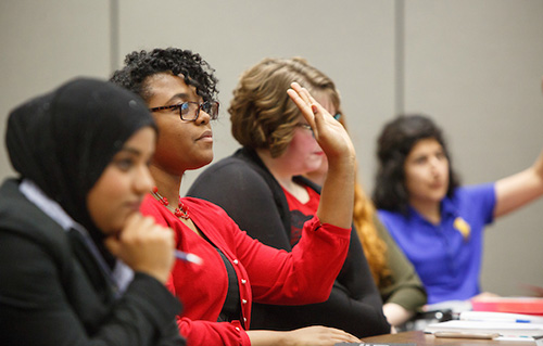 Individuals raise their hands in a meeting.