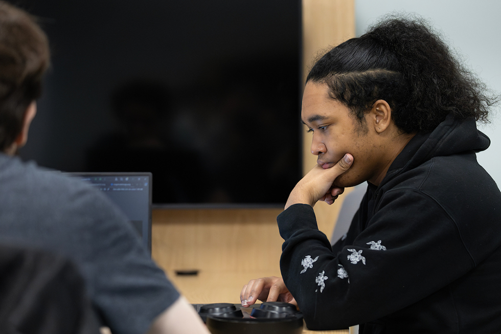 A student in a black hoodie looks thoughtfully off screen. The text reads "Wear Black, Give Back" with one red buttons to make a monetary donation to Student Legal Services.