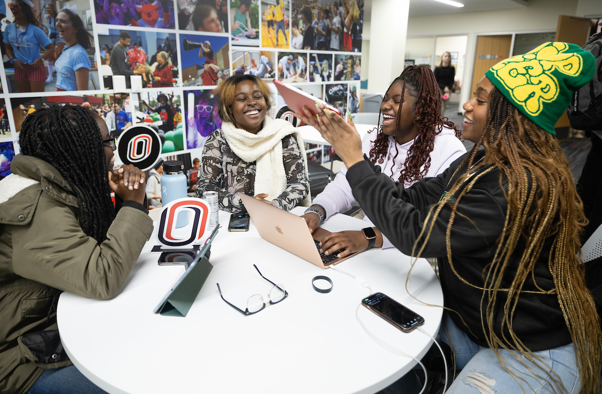 Students sitting around a table and laughing together.